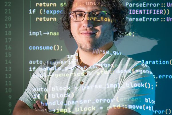 An SDL Intern standing in front of code.