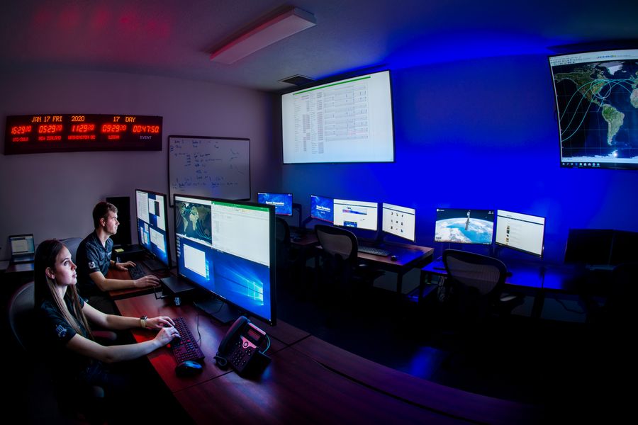 Two operators inside a satellite mission operations center.