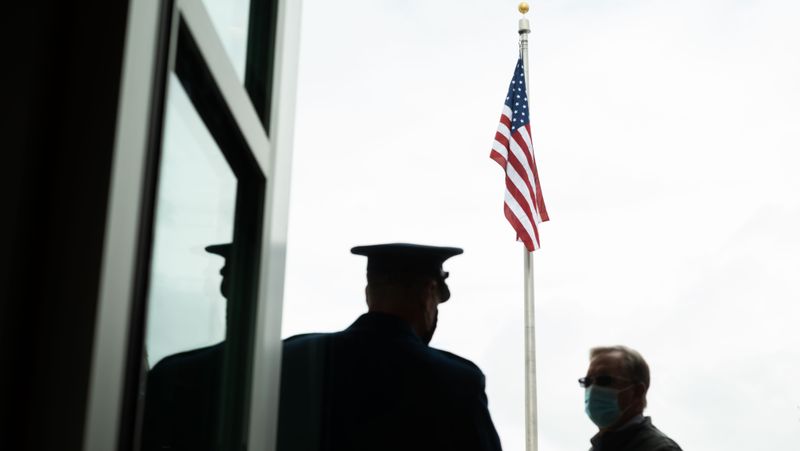 Person standing next to an American flag.