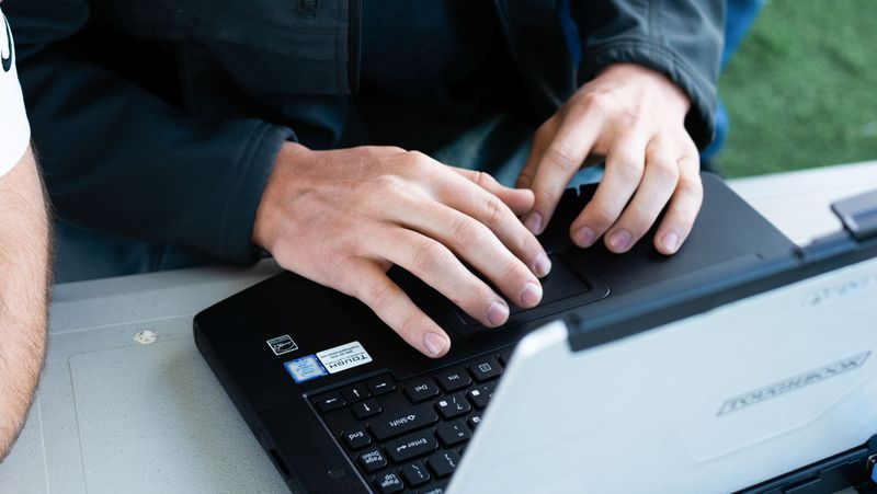 A person using a laptop outside to communicate with a UAS.