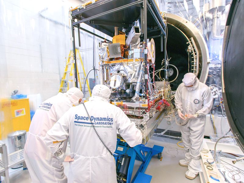 Staff working with the ICON science instrument in a high bay.