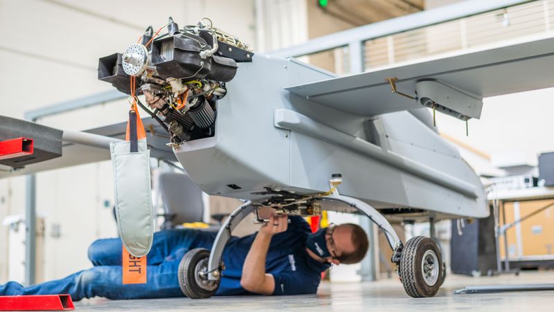 A person attaching a sensor to a UAS in the hangar.