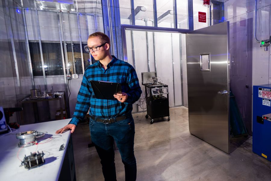 An engineer with hardware components in the small satellite propulsion testing center.