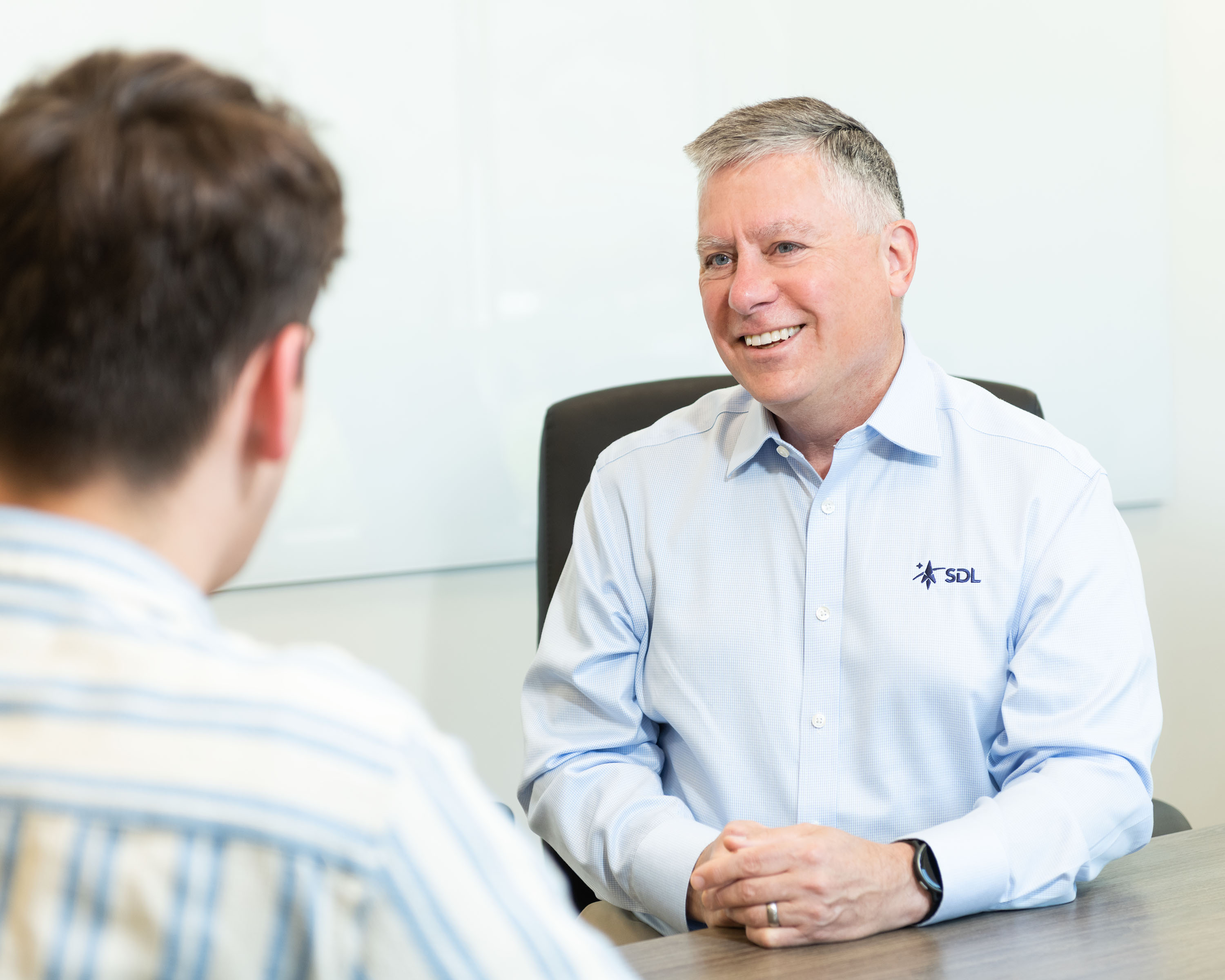 John Robson sitting at a conference room table with a colleague.