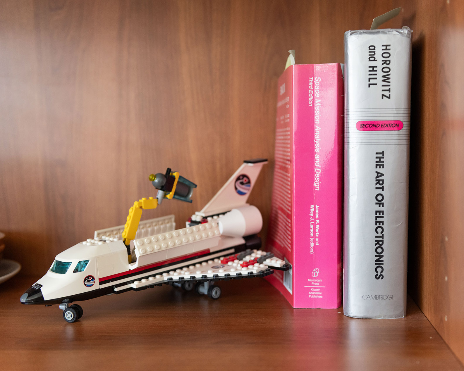 A Lego space shuttle model with an open payload bay displayed on a bookshelf.